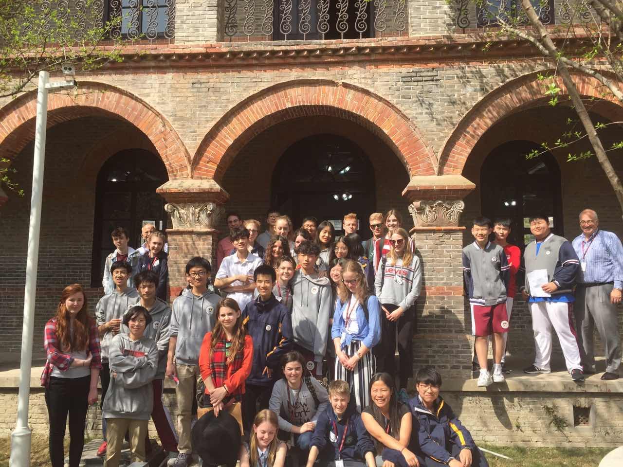 Students and educators gathered outside a historic brick building with arched entrances during a GSE exchange in China.